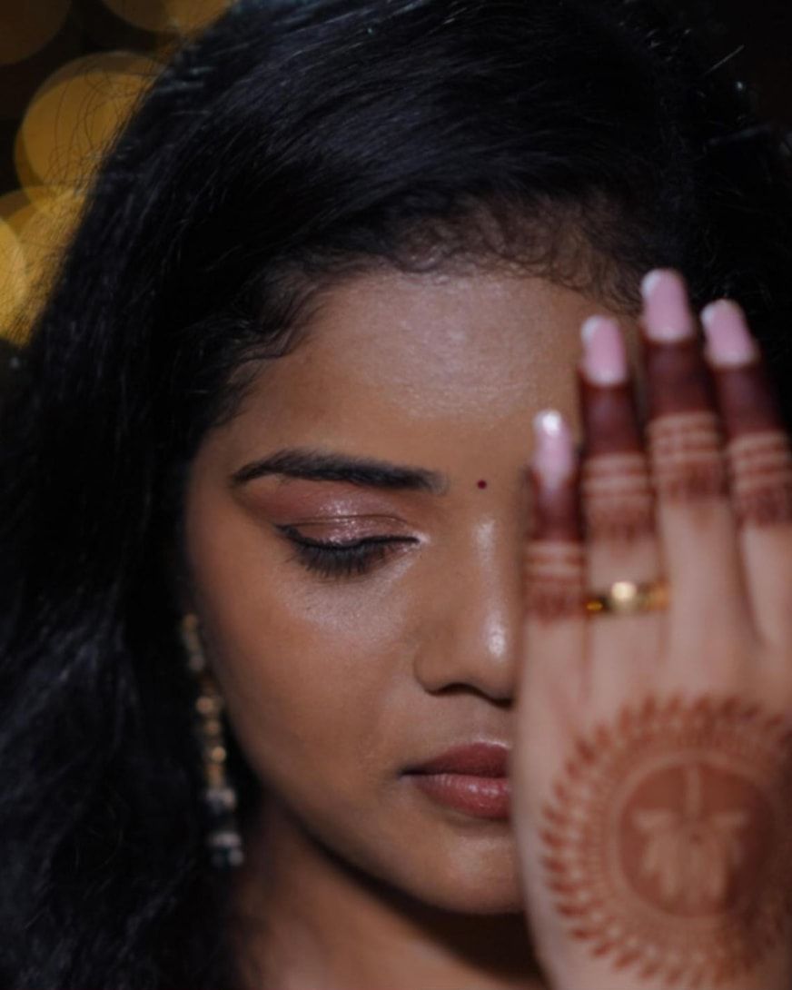 Close-up of shimmer eye makeup with a henna-decorated hand