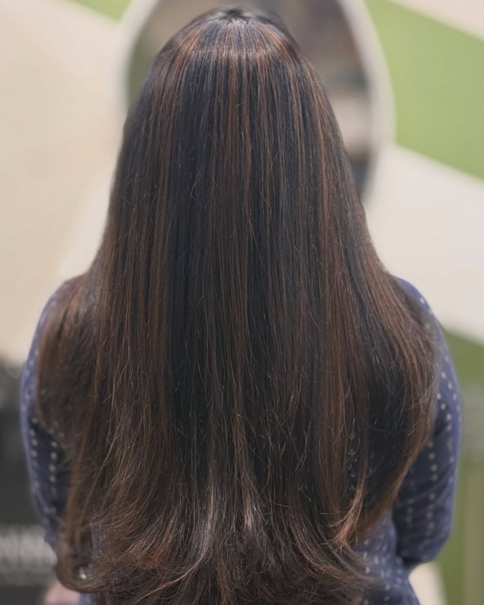 Long layered hair with warm brown highlights, seen from behind